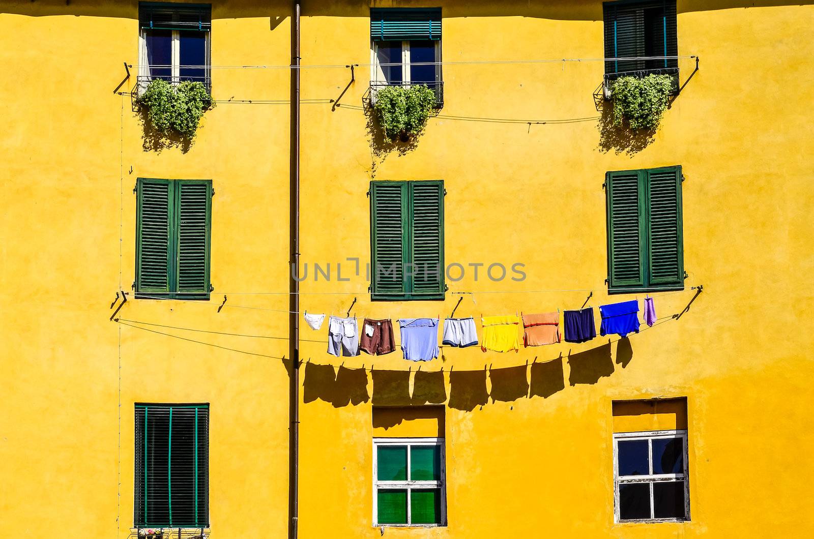 Detail of colorful yellow house walls, windows and drying clothes