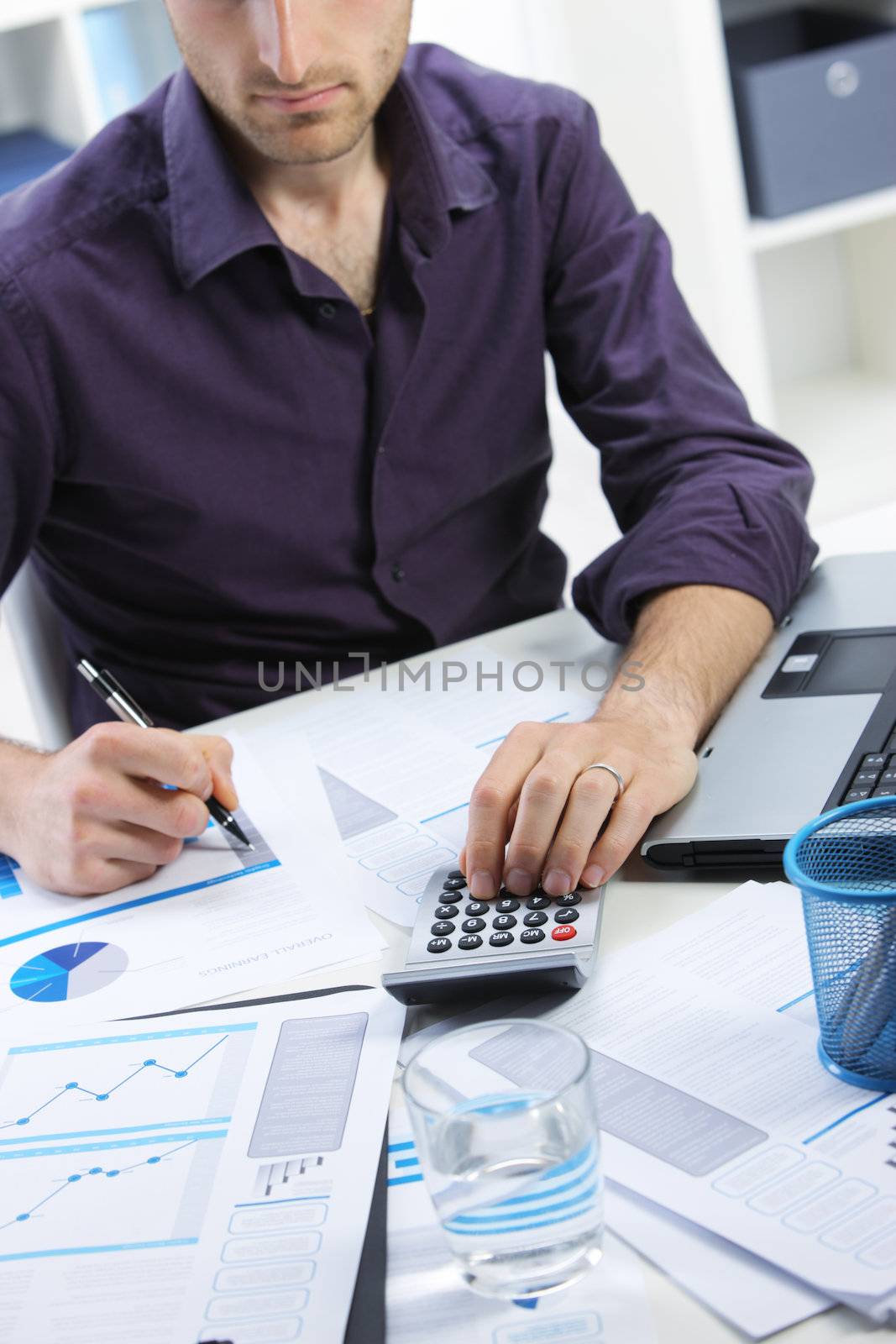 Business man checking financial data on calculator.