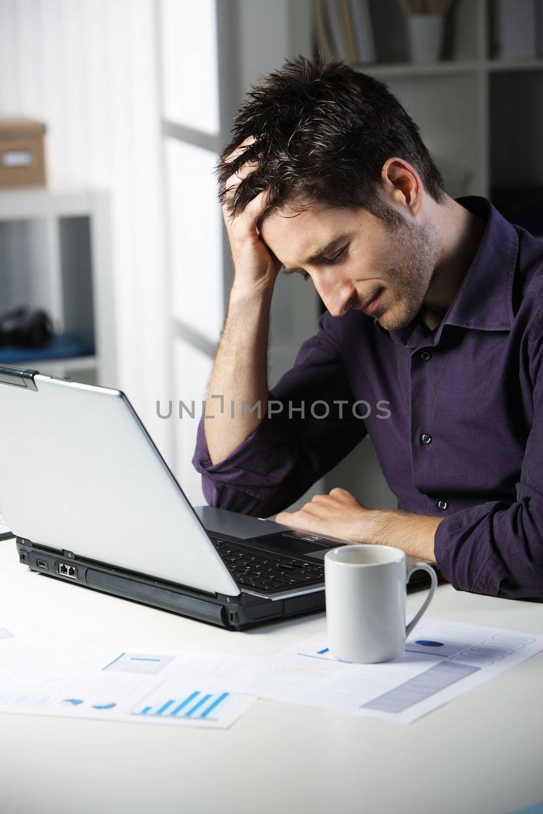 Stressful young man working on laptop
