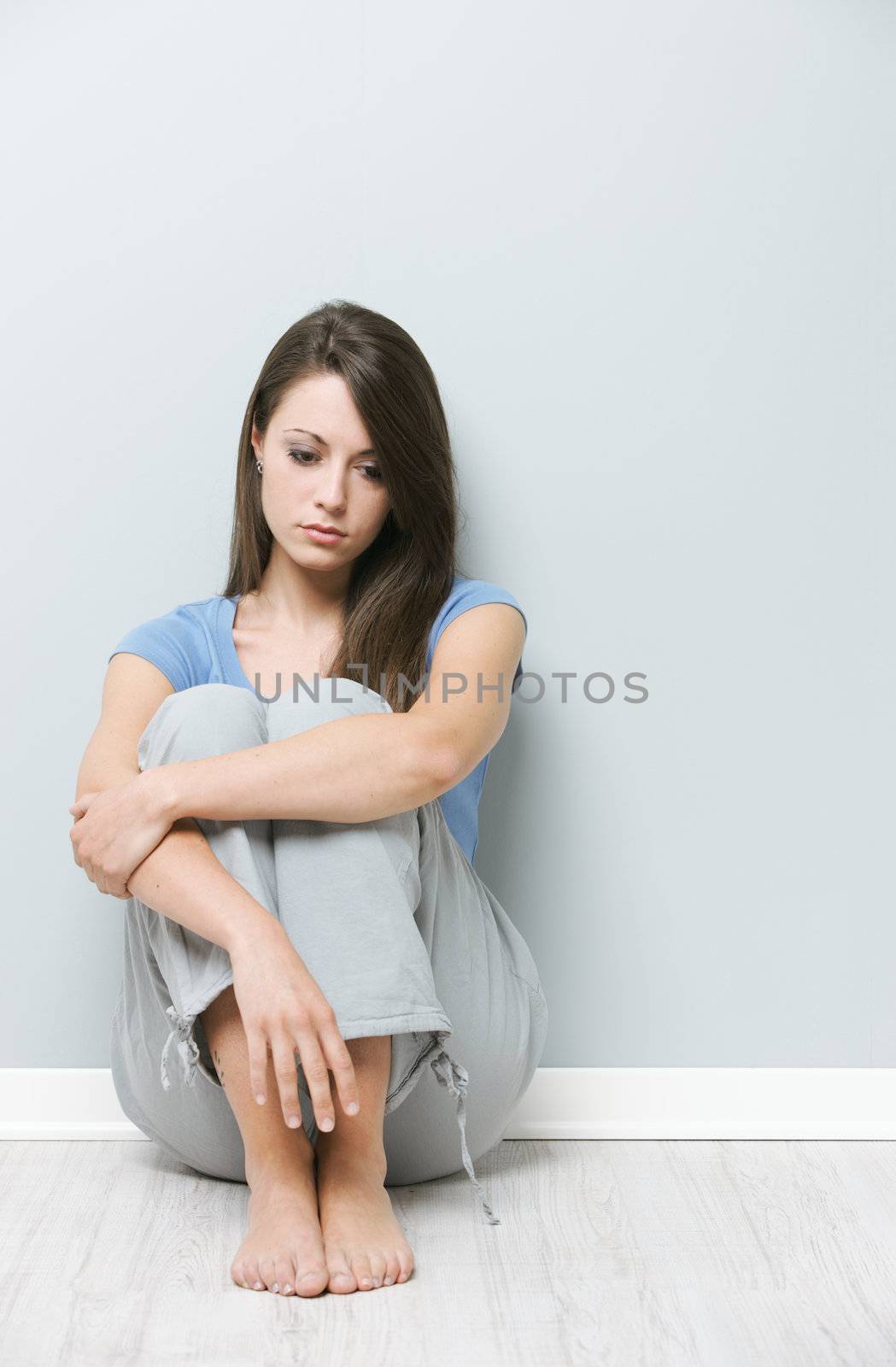 Young sad woman sitting on floor at home 