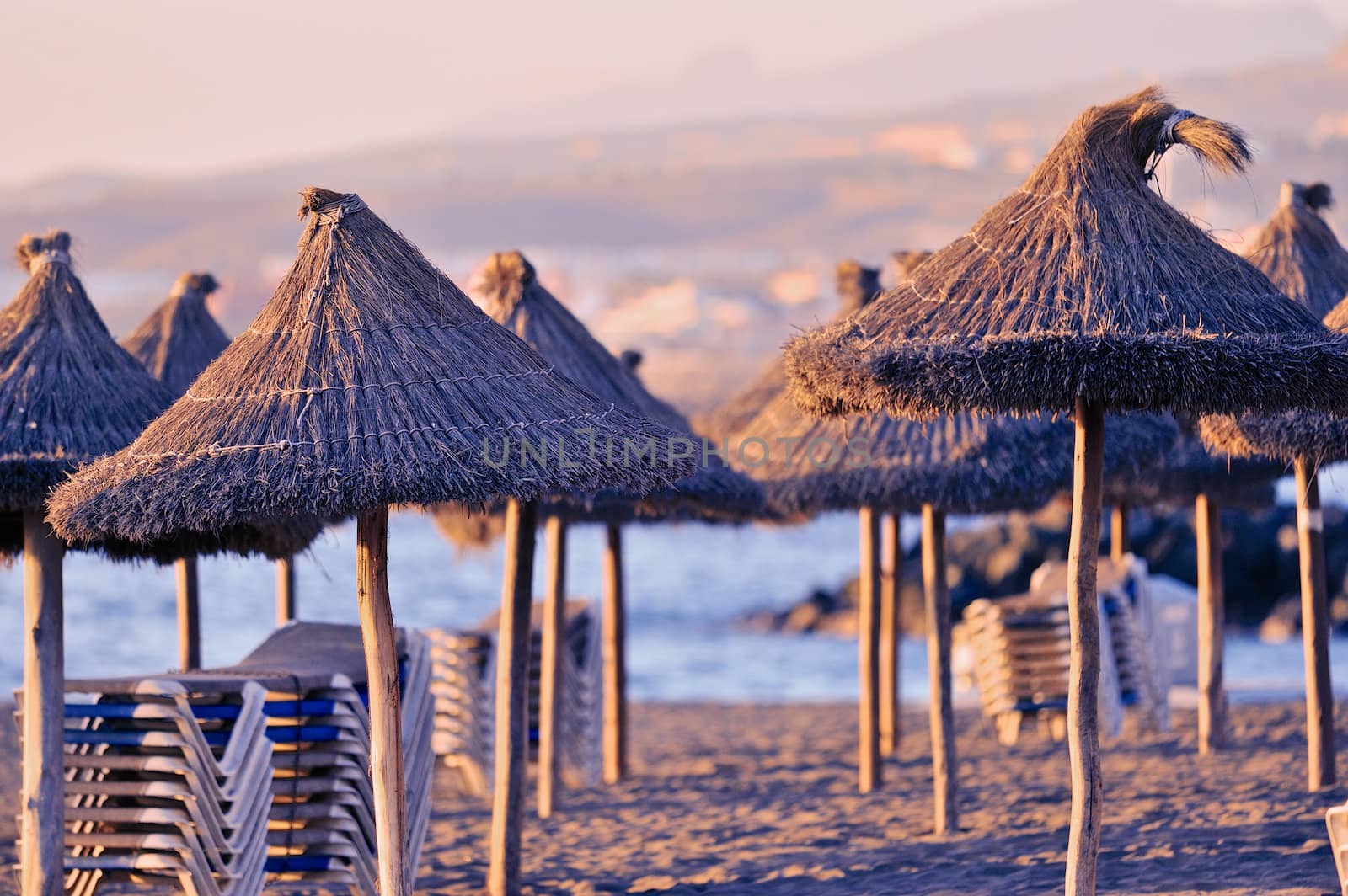 Row of straw sunshades on the sea coast