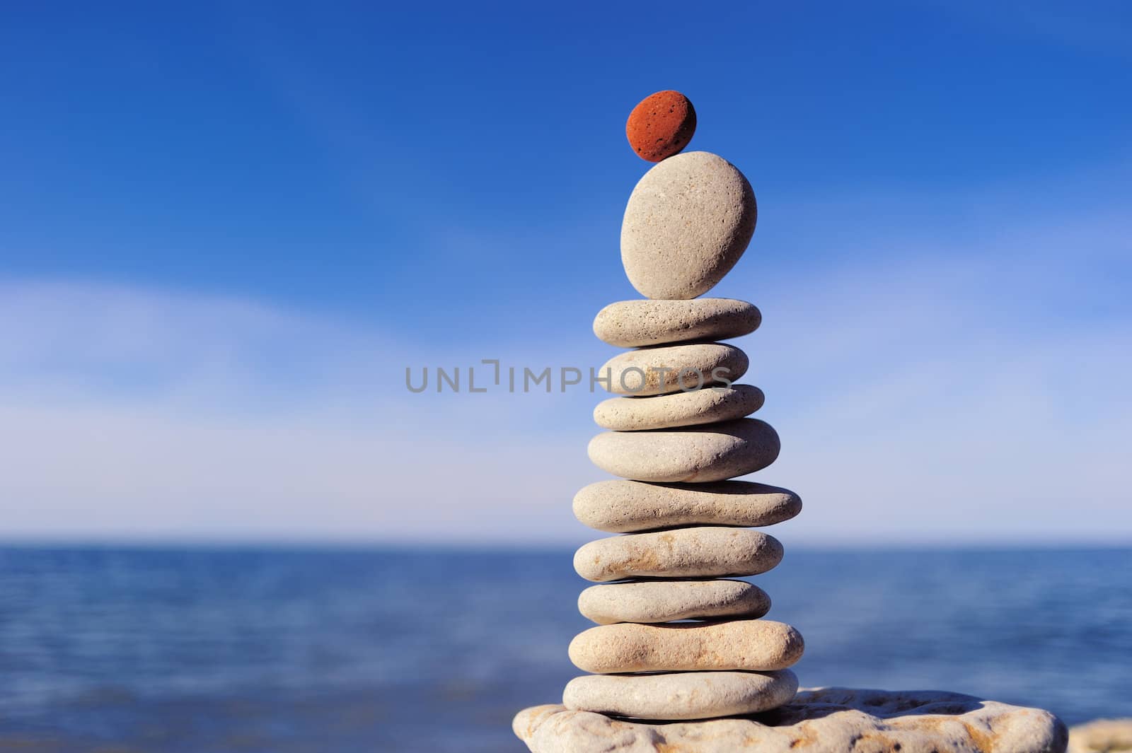 Balance of red stone on the top of stack of white pebbles