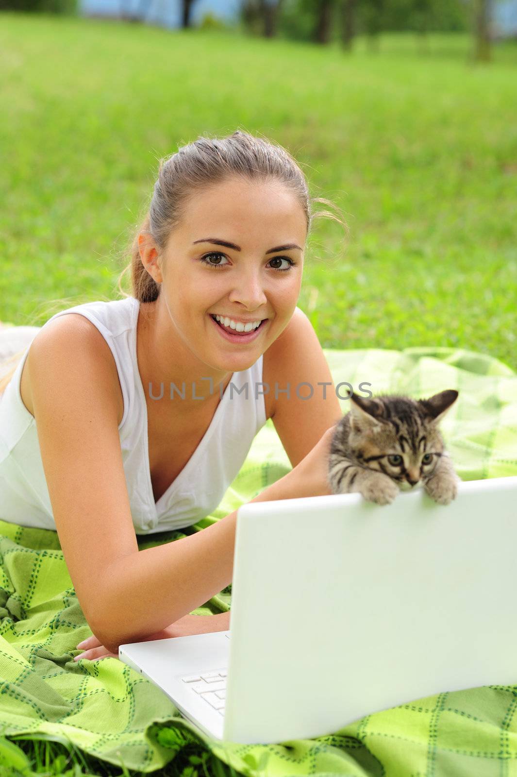 Happy young woman with her kitty and laptop outdoors