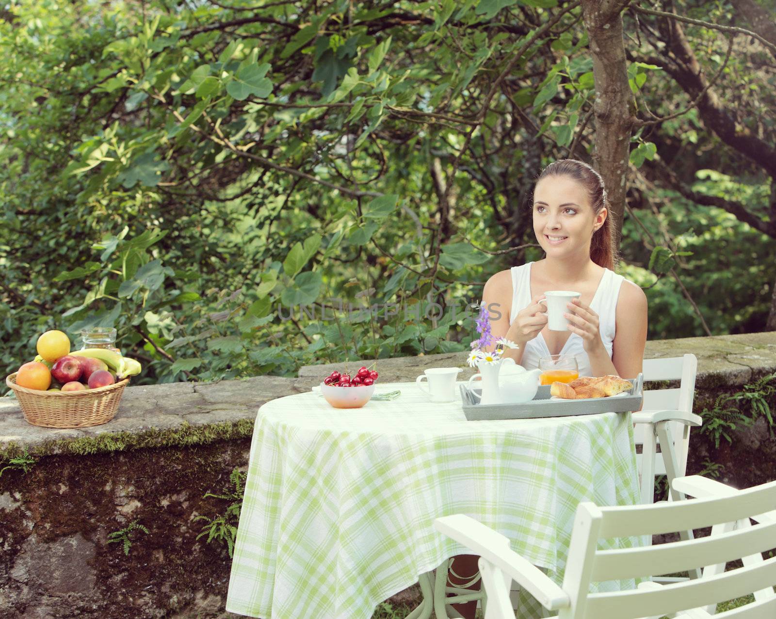 Young woman having breakfast in the garden on a summer day