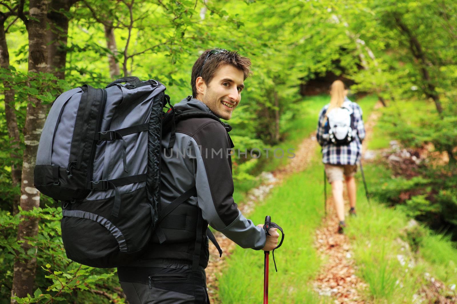 Young couple enjoying a nordic walk, man looking at camera and smiling