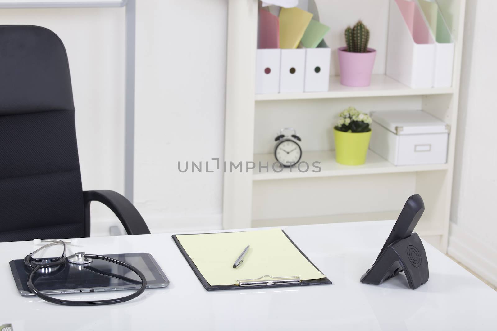 Doctor office table desk and black chair with stethoscope  and white paper