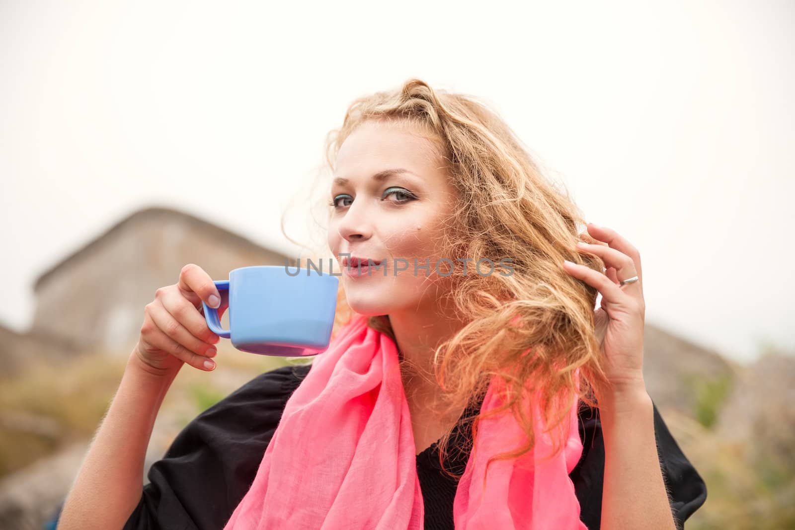 Young happy smiling woman drinking coffee outdoors.