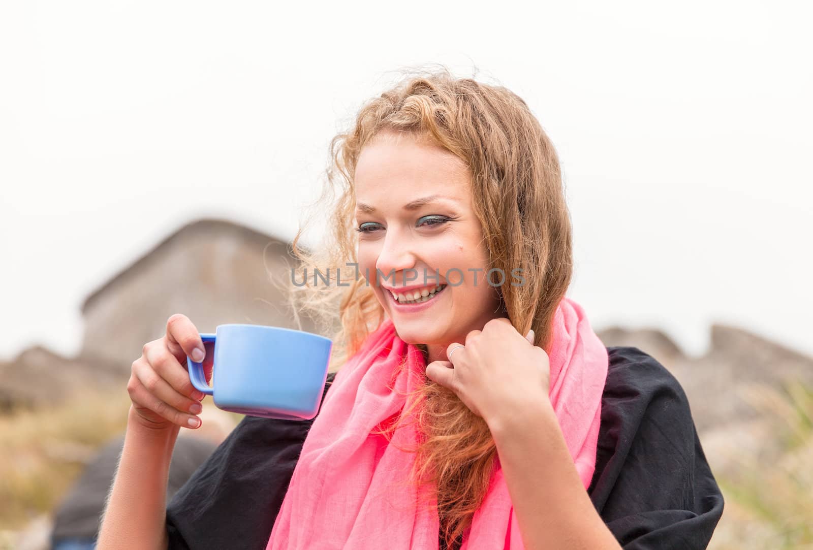 Young happy smiling woman drinking coffee outdoors.