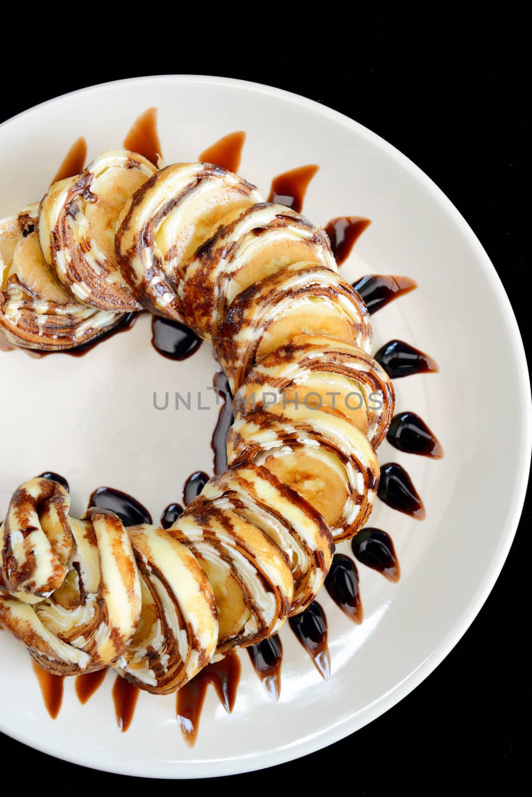 homemade crepe banana with chocolate sauce isolated on black background