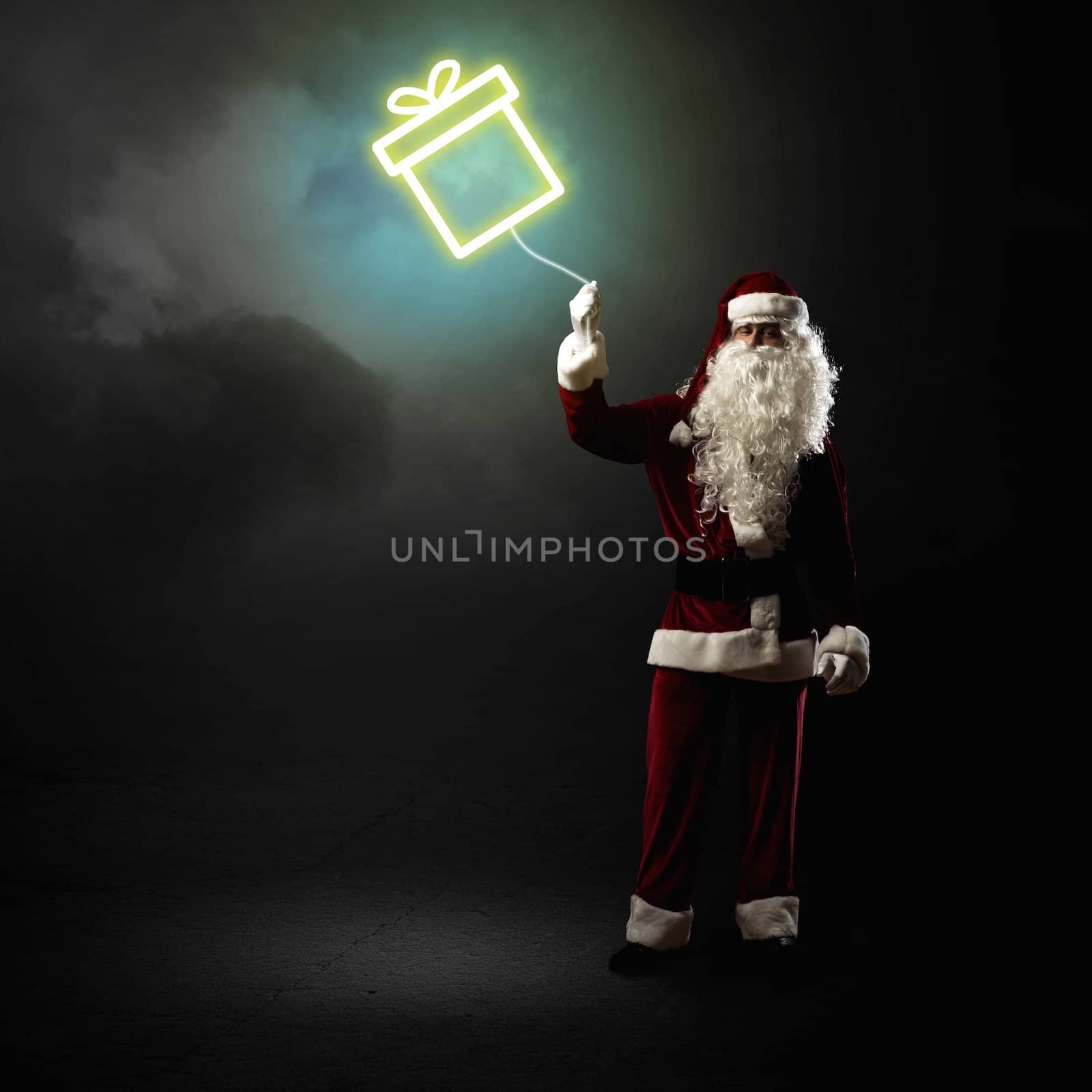 Santa Claus is holding a shining symbol of the gift on a string