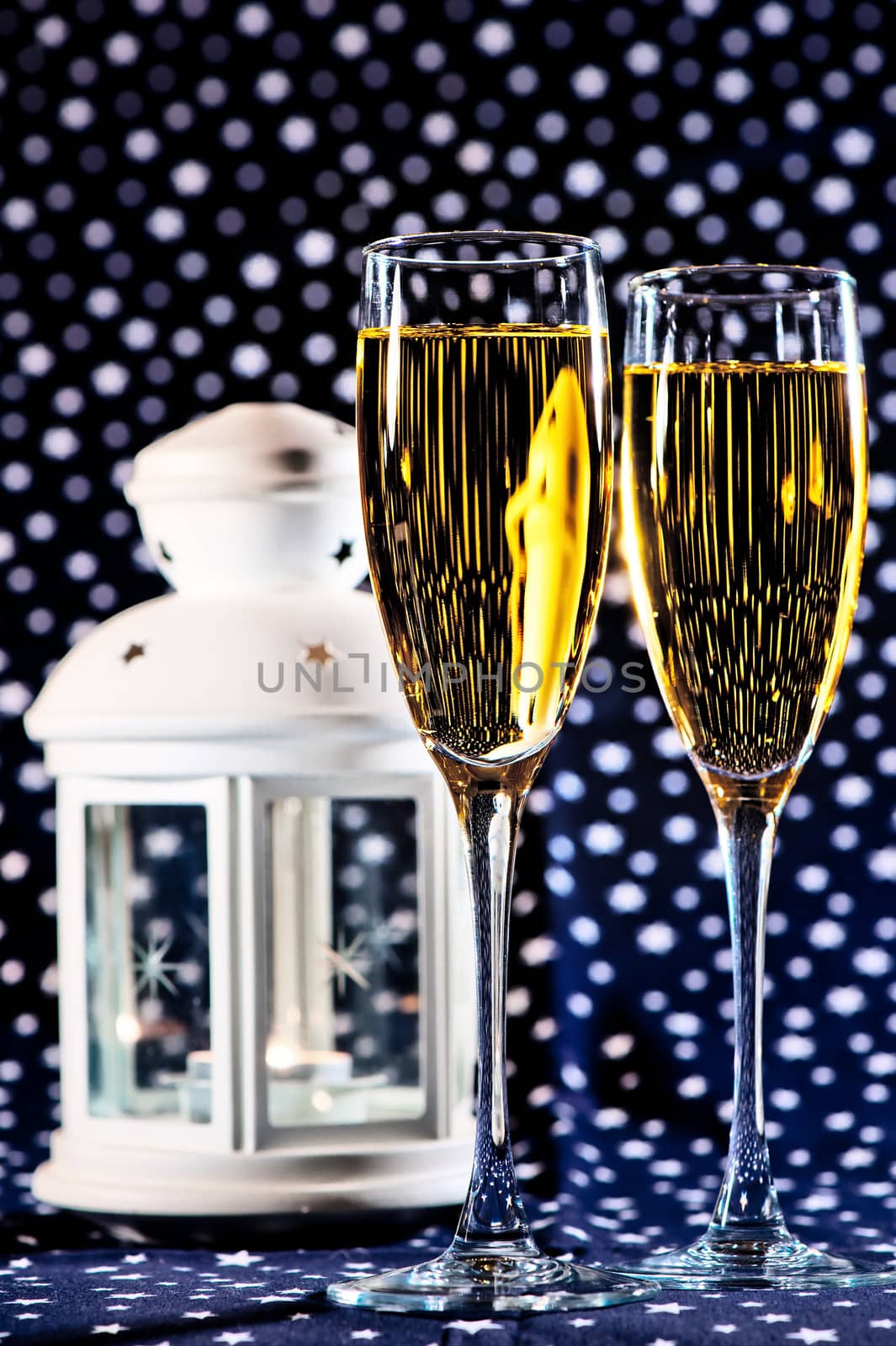 Two glasses of champagne and a white lantern on a star background