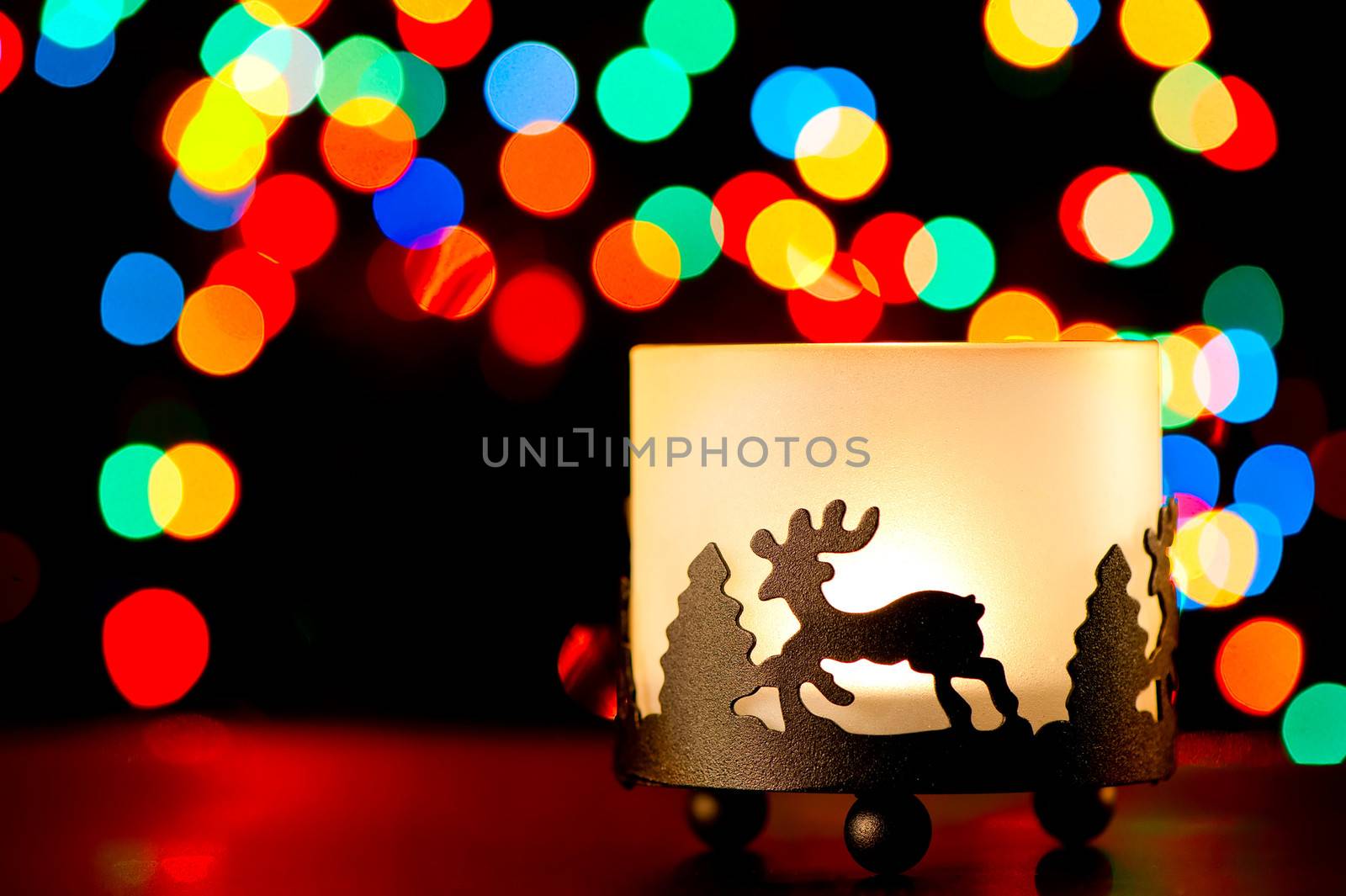 Candlestick with a figure of a deer on the background of blurred lights garlands.