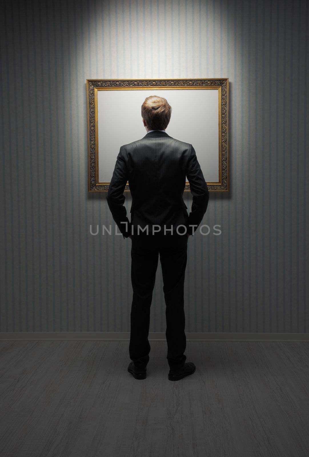 A young man standing in front a empty frame in a museum