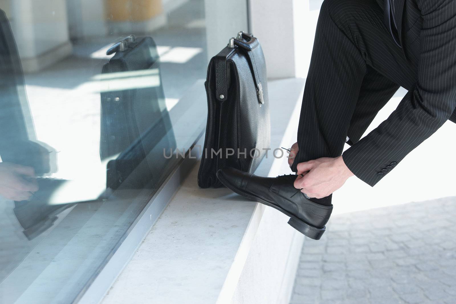 A businessman  wearing a suit is tying his shoes