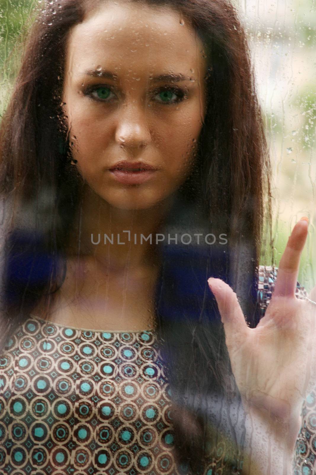 Portrait of a young woman near the window after the rain