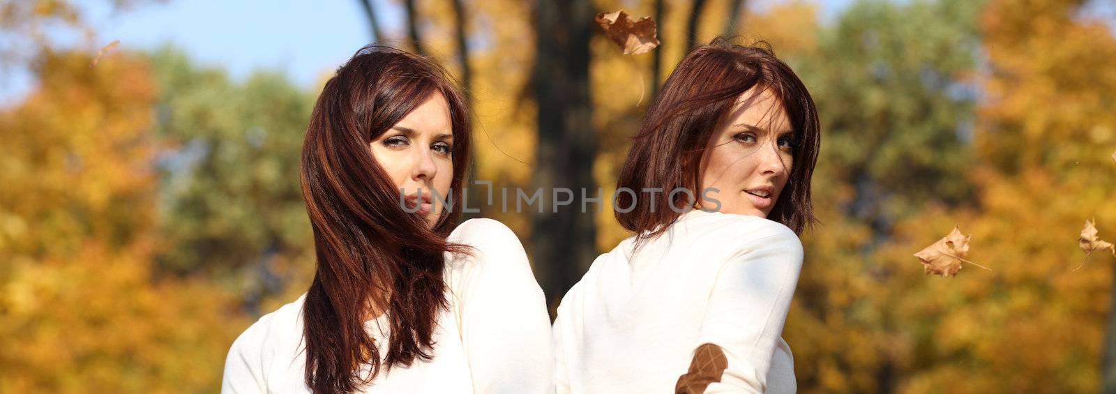 Smiling young attractive women with autumn maple leaves in park at fall outdoors