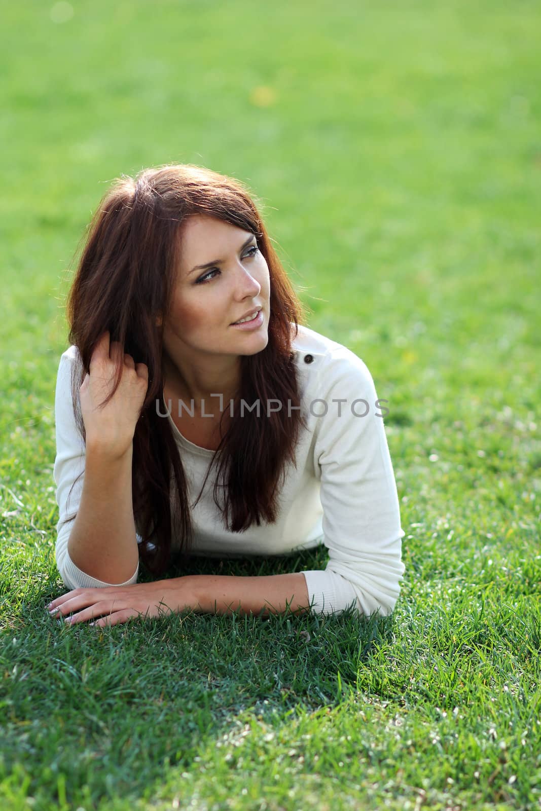 Portrait of young woman lying on a green lawn