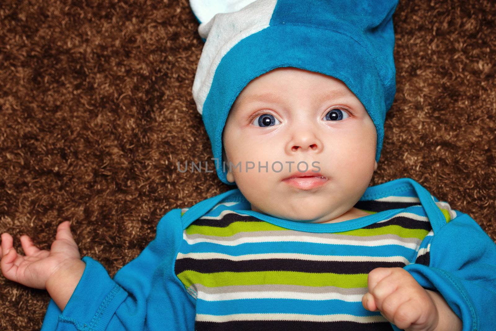 Blue-eyed baby lies on his back and smiling while looking at the camera