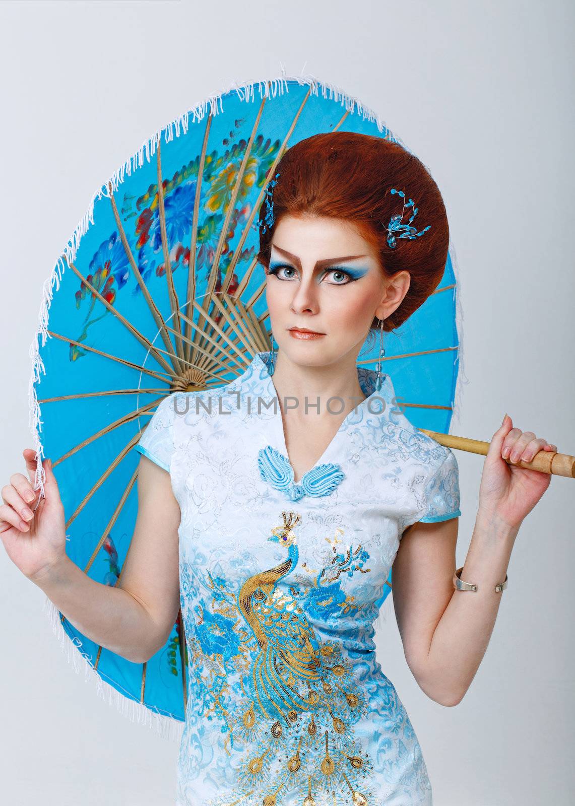 Attractive geisha in a smart dress with an umbrella, photographed in the studio