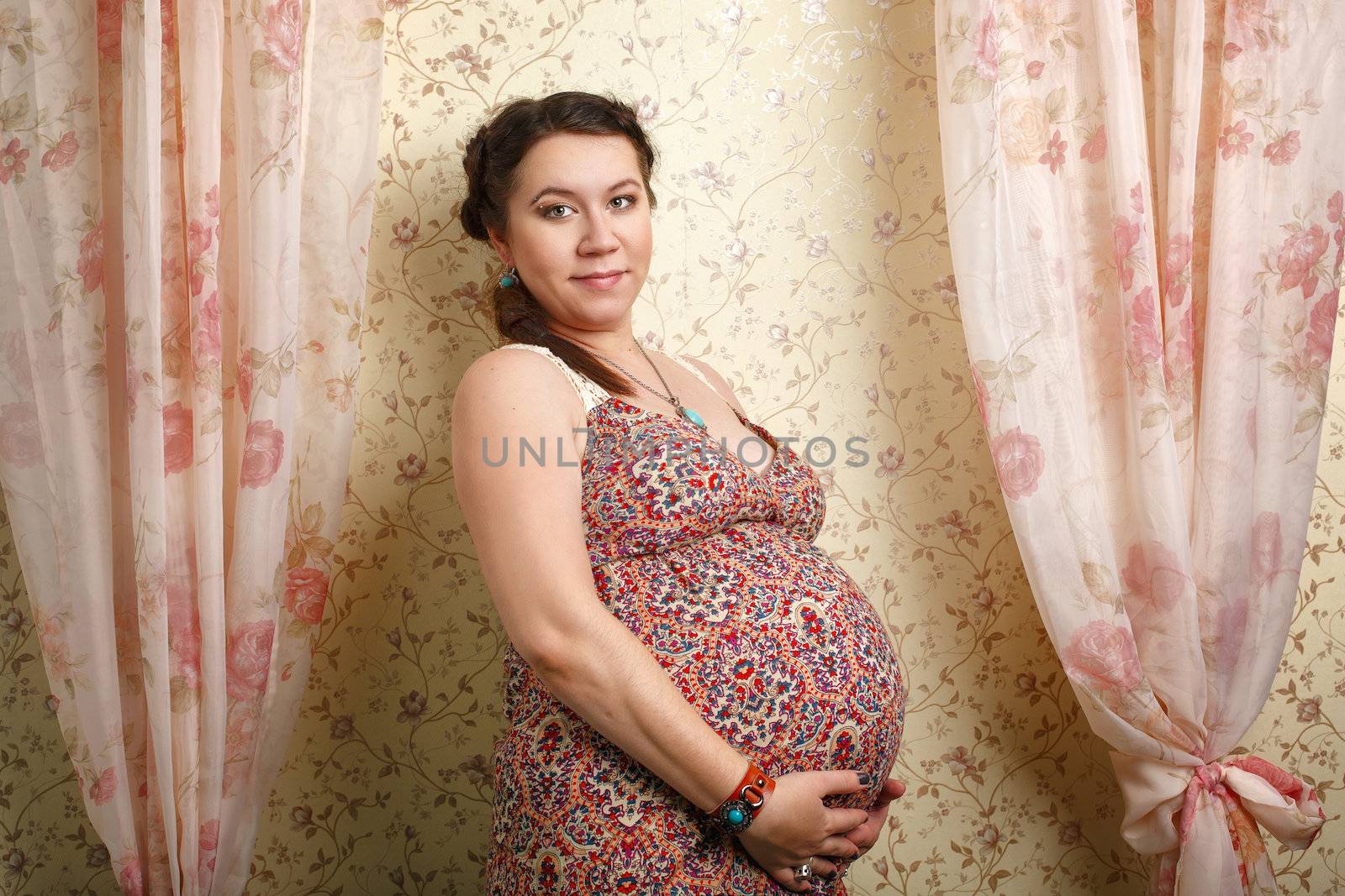 Beautiful pregnant girl on a large stage of pregnancy photographed in the studio