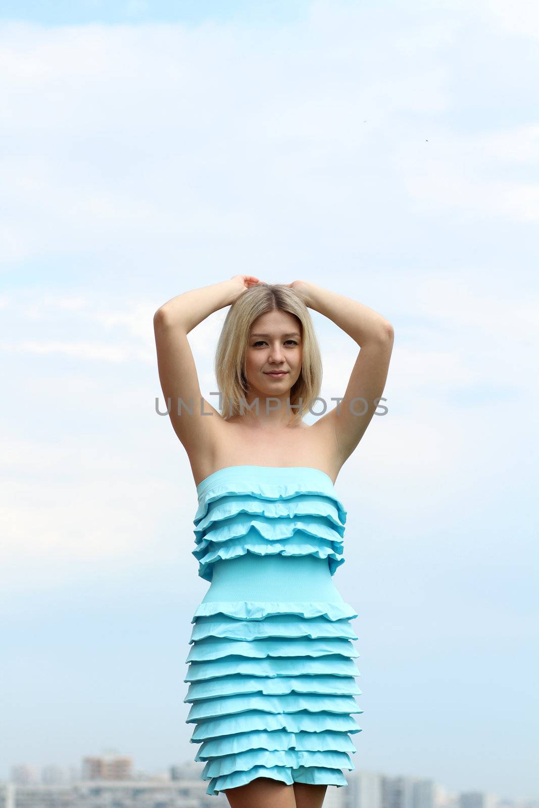 Young blond woman in sexy dress on background of the sky