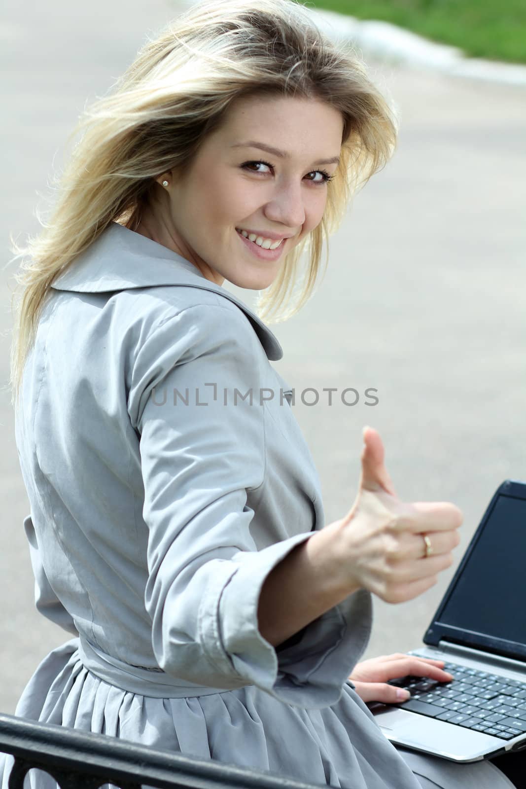 Girl using laptop while sitting on bench at spring park