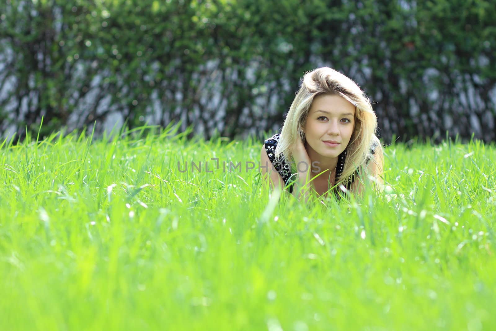 Cute young female lying on grass field at the park