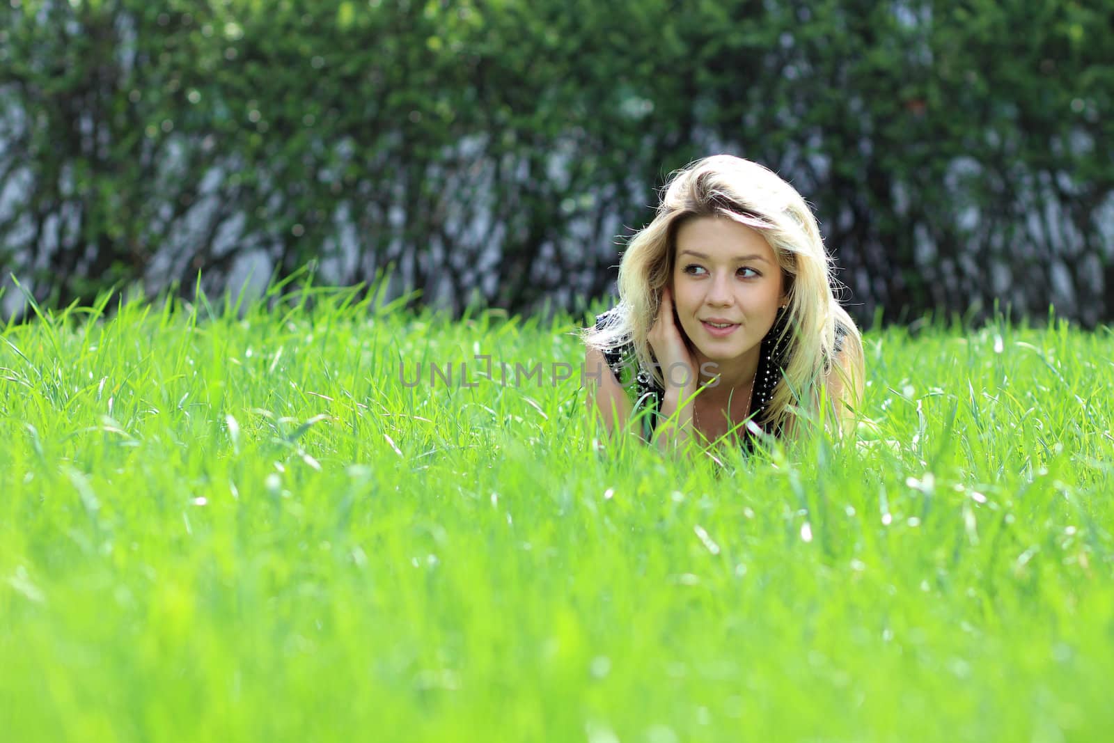 Cute young female lying on grass field at the park
