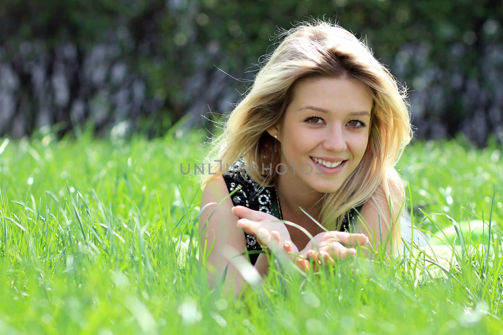 Cute young female lying on grass field at the park