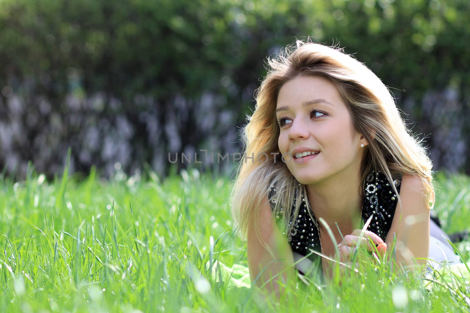 Cute young female lying on grass field at the park