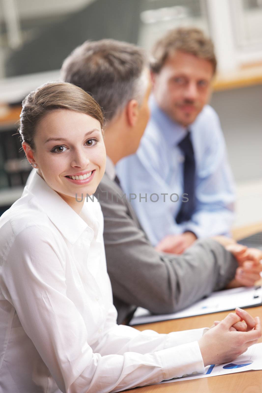 Smiling woman sitting at a business meeting with colleagues by stokkete