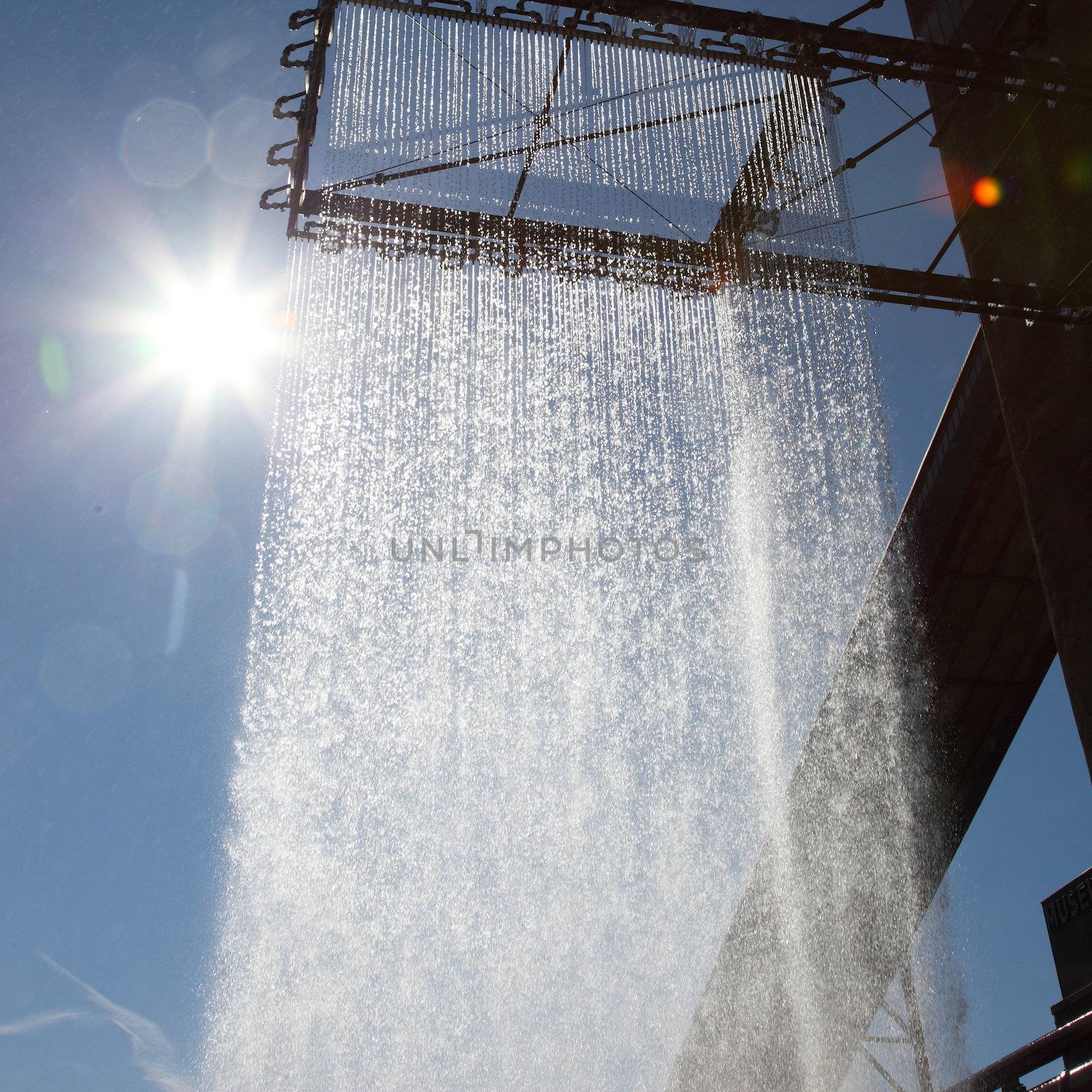 Decorative curtain of falling water on the exterior of a building or structure sparkling in the hot rays of the sun