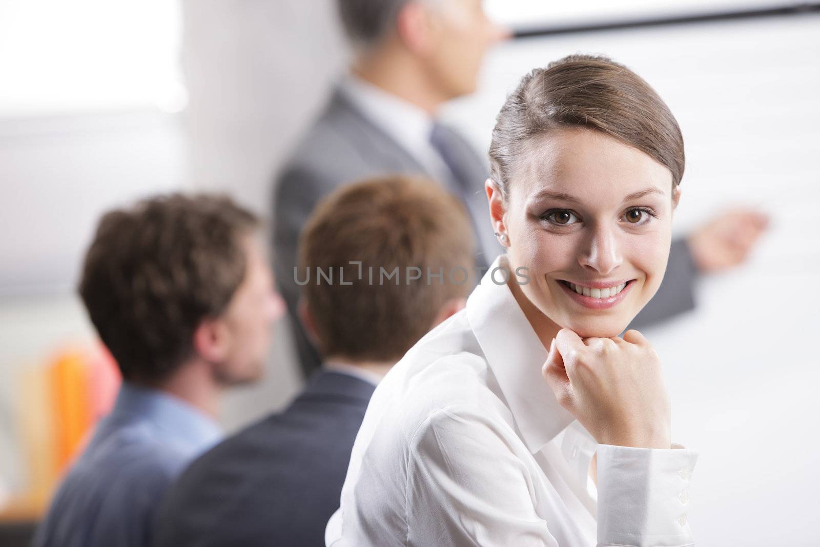 Young businesswoman smiling in a meeting with her colleagues in background