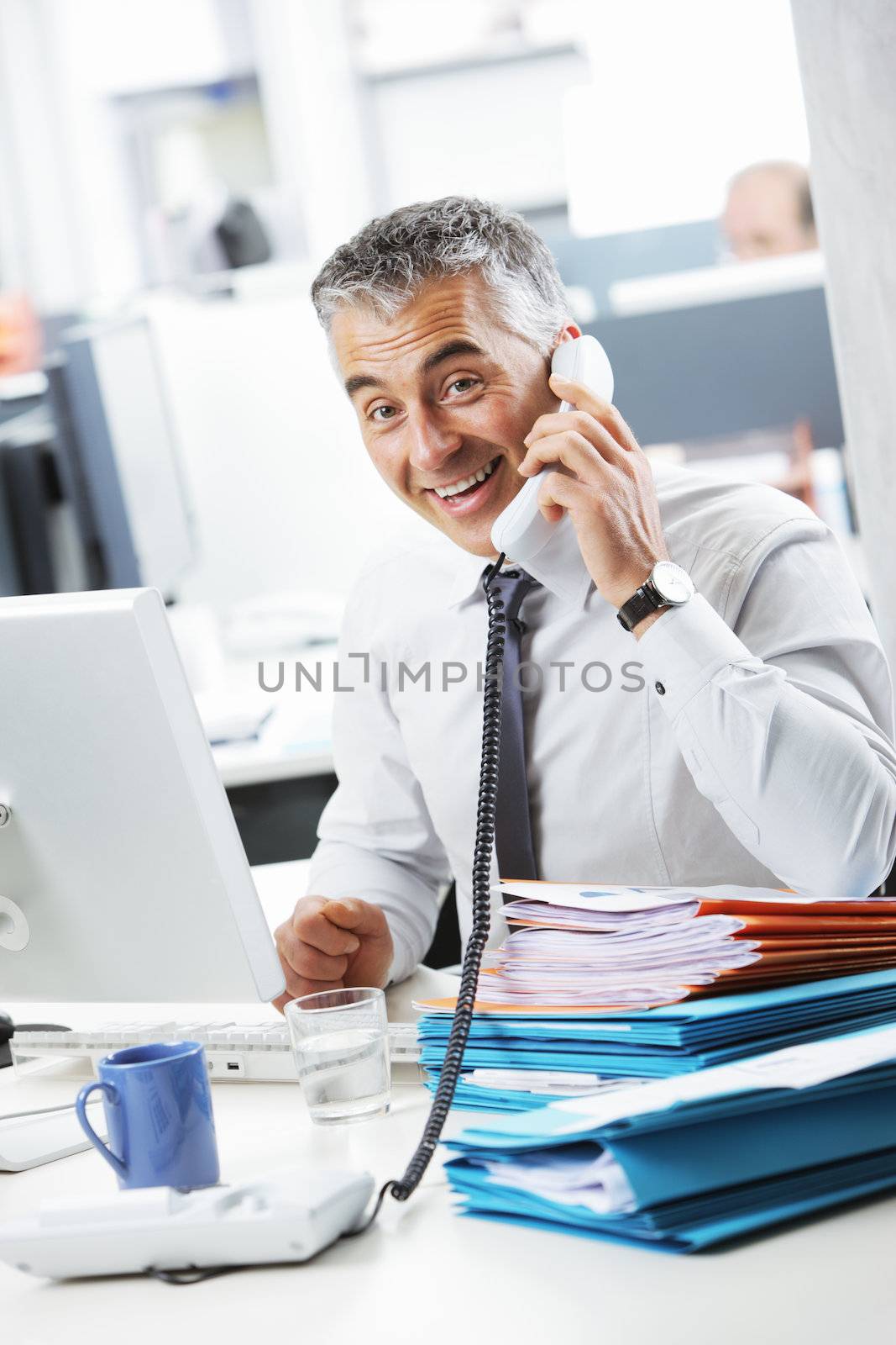 Mature business man talking at phone in office