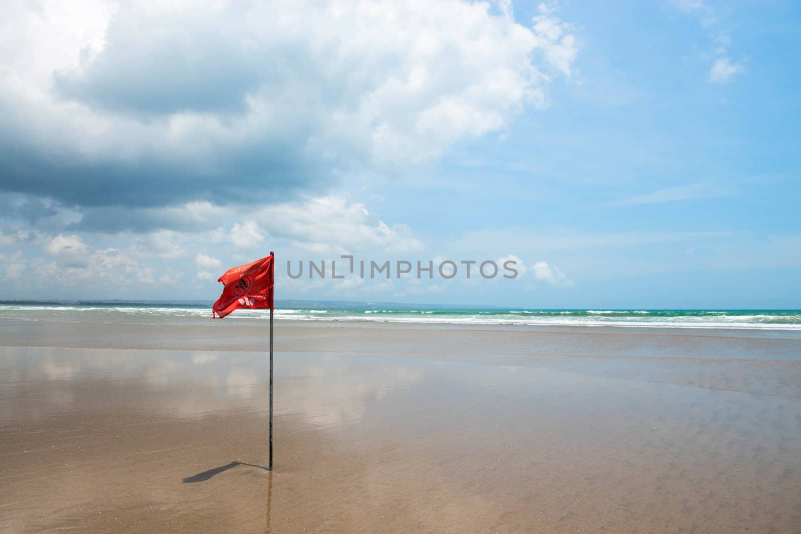 Red flag on beach with no swimming notes. Season of storms and strong currents.
