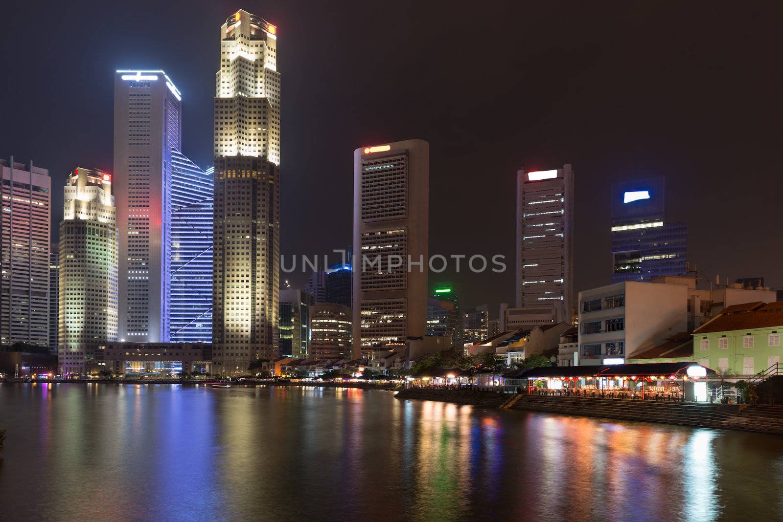 Singapore quay at night with tall skyscrapers in the central business district and and small restaurants on Boat Quay 