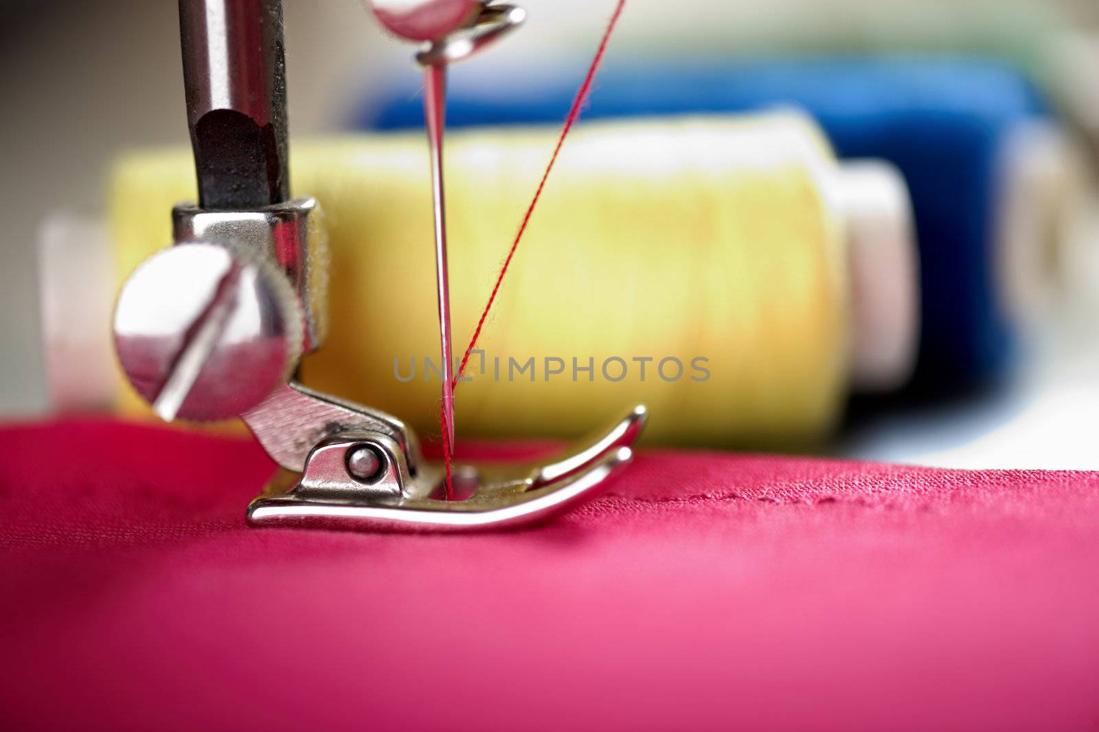 Close up of threads on fabric and sewing machine. Shalow DOF. Selective focus. Focus on blue threads.