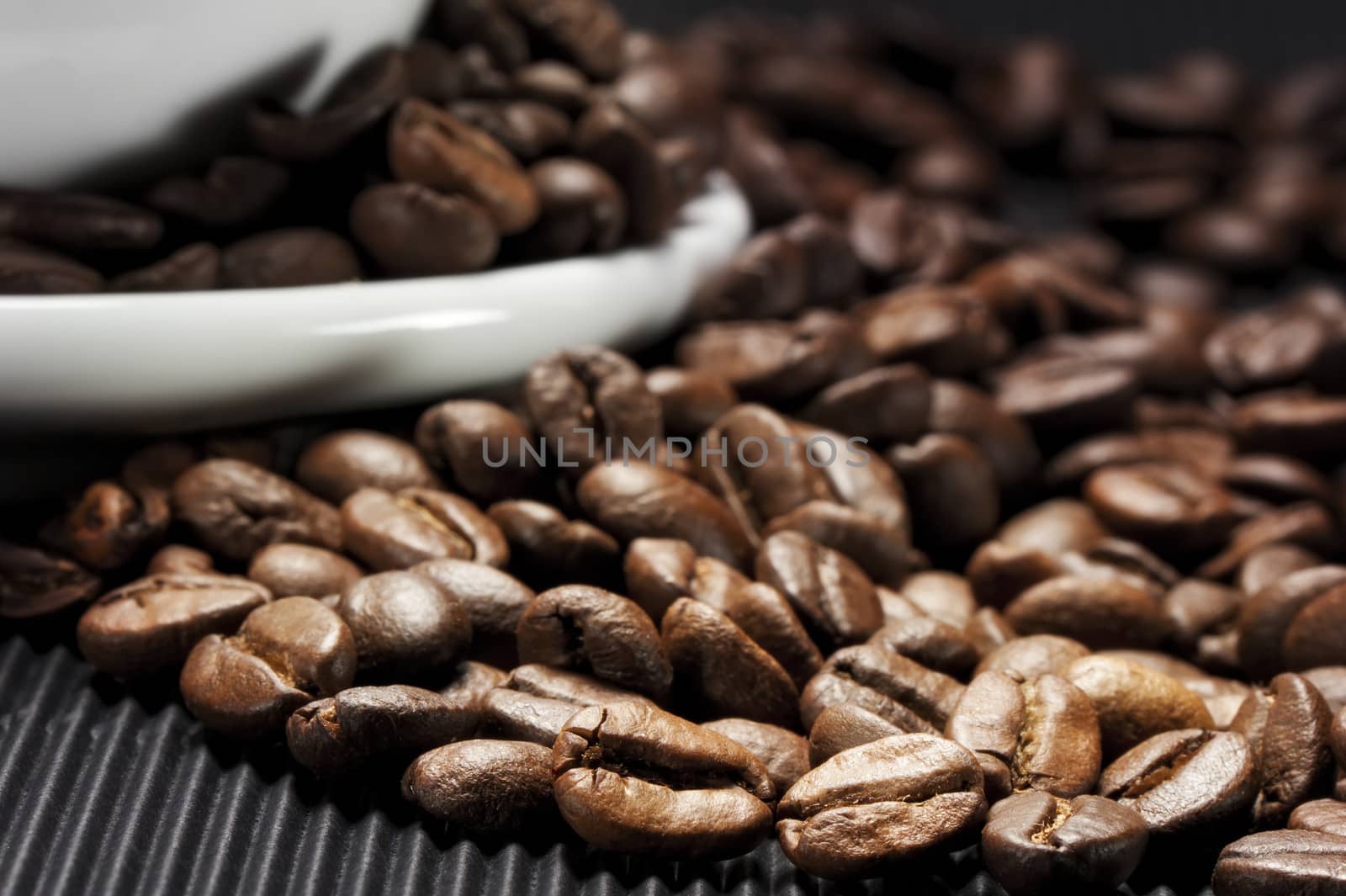 Coffee beans scattered on a black grooved