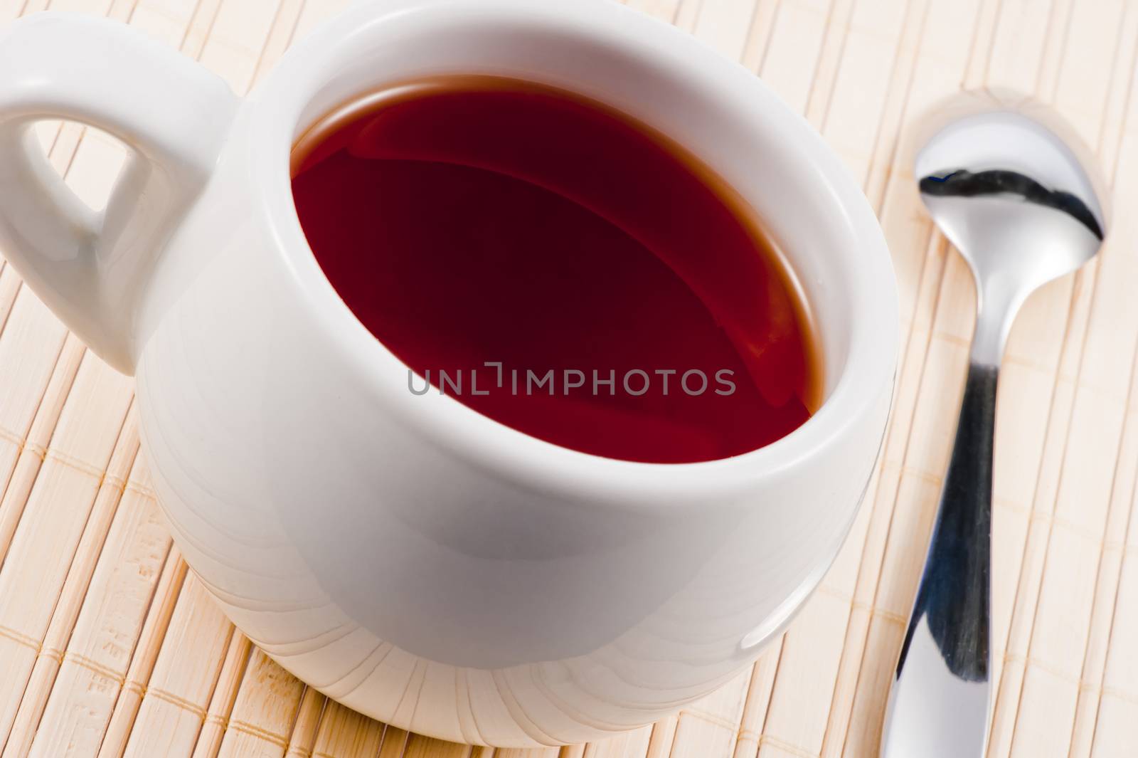 White cup with fresh tea on wooden mat. by kosmsos111