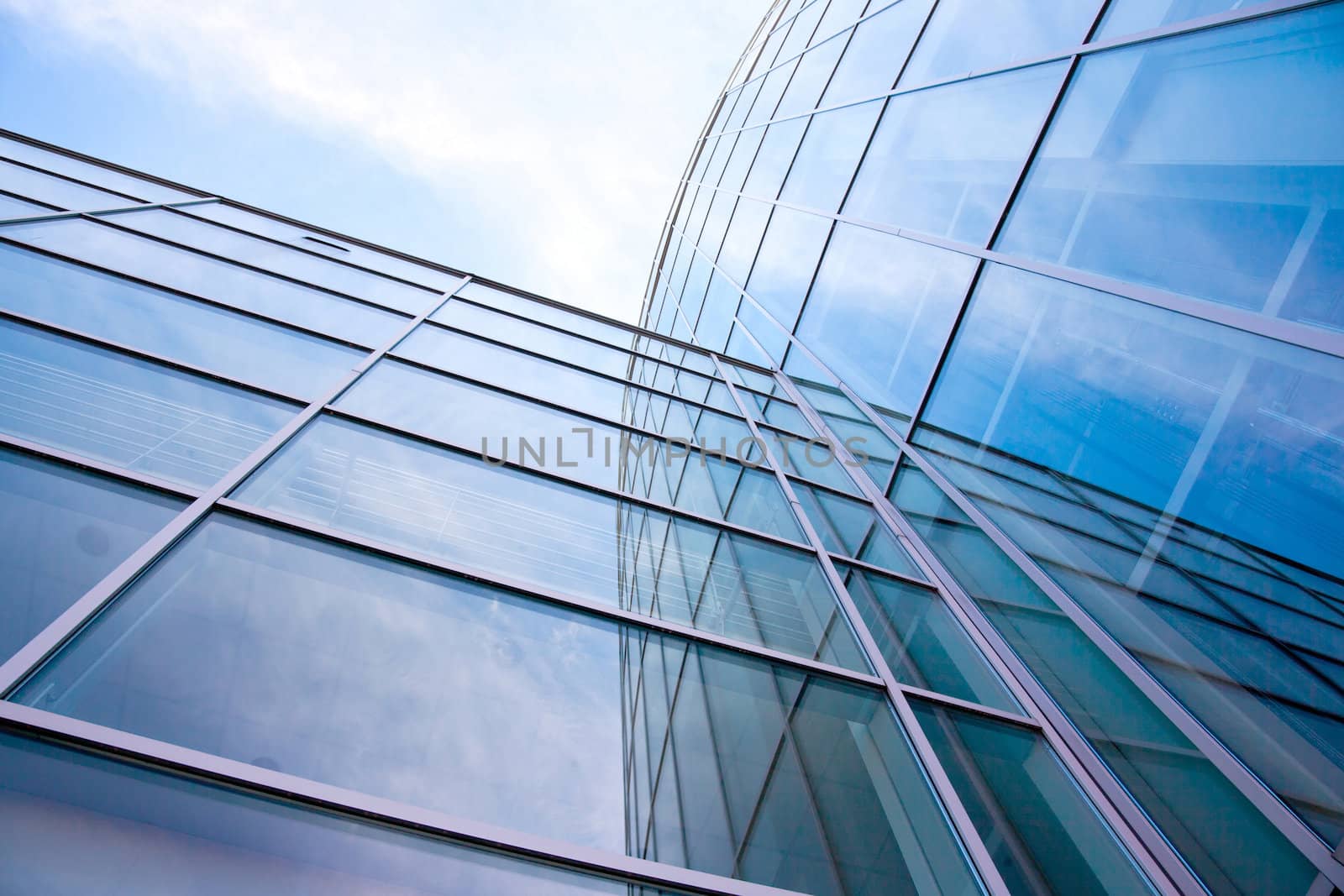 facade of modern glass blue office and clouds by ahavelaar