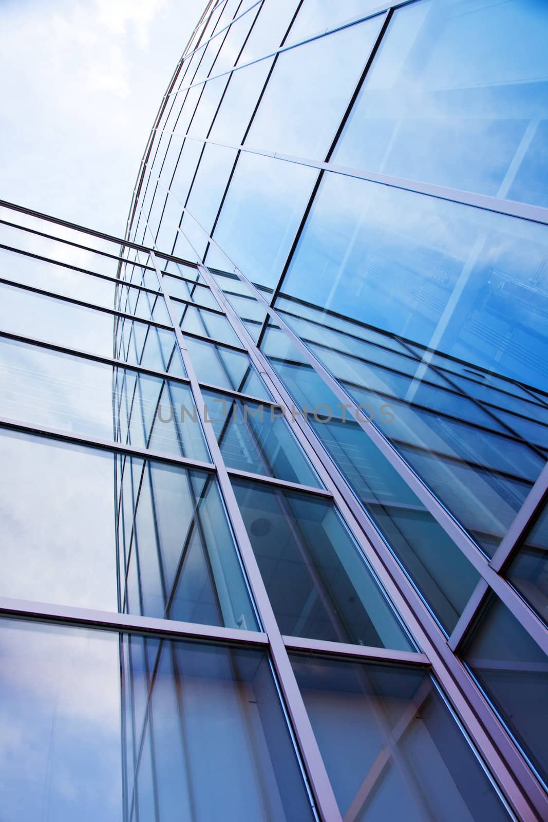 vertical imgage of facade of modern glass blue office and sky with clouds reflected