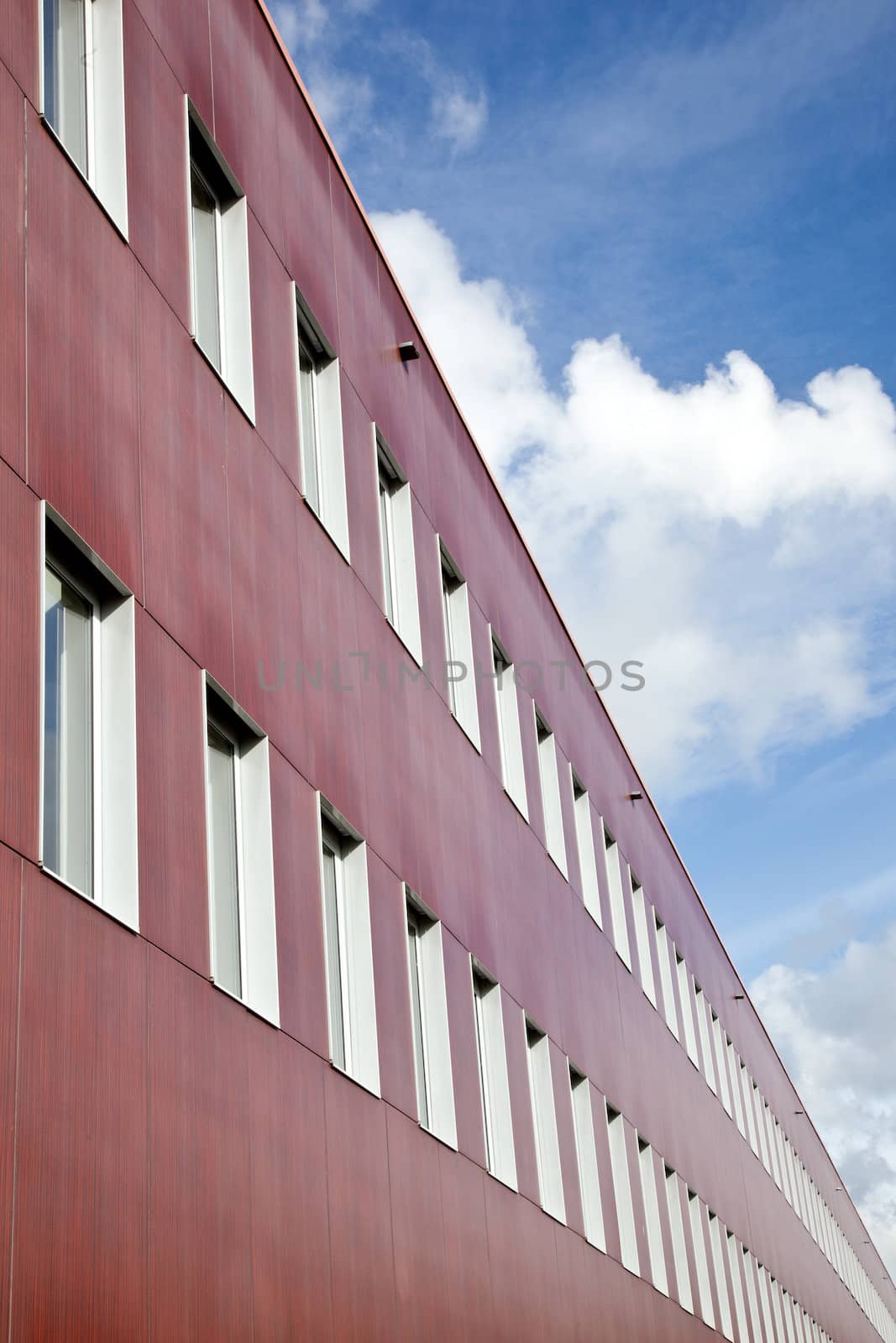 red wall of office building and clouds by ahavelaar