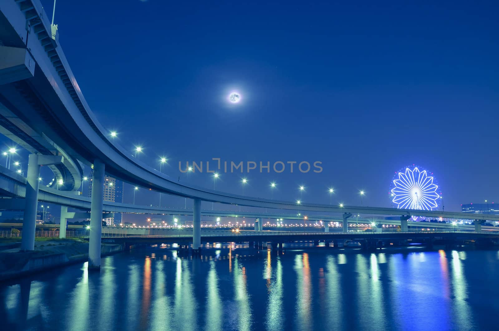  hanged-up highway road over Tokyo bay waters at night time with moon and ferris-wheel illumination on backward