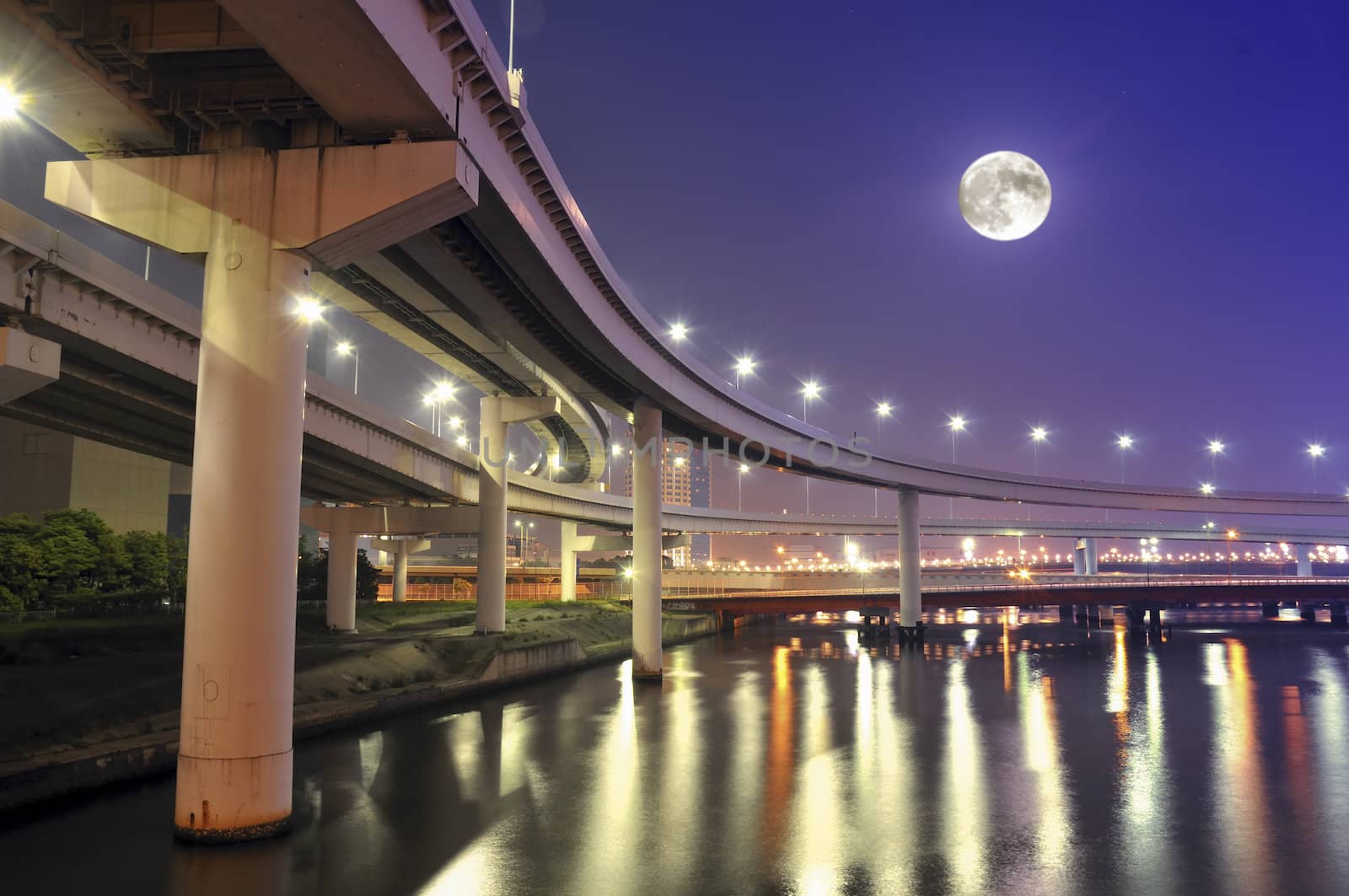  hanged-up highway road over Tokyo bay waters at night time with full moon in the sky