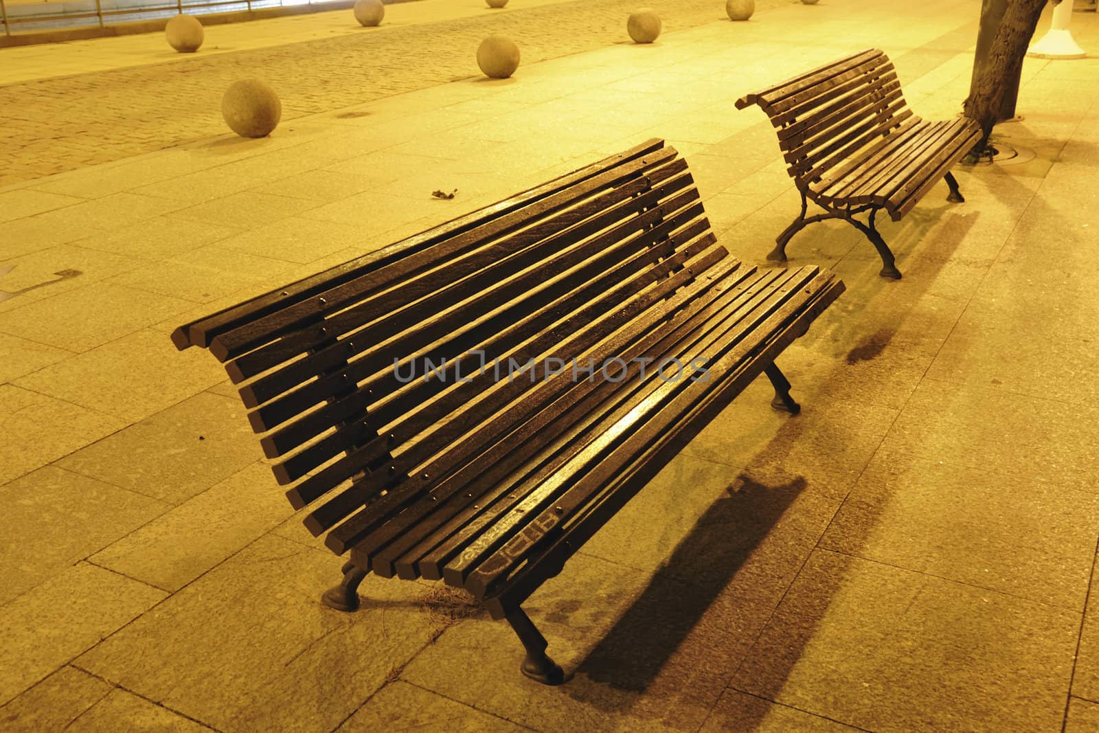 scenic city benches under yellow night illumination along pedestrian walkway