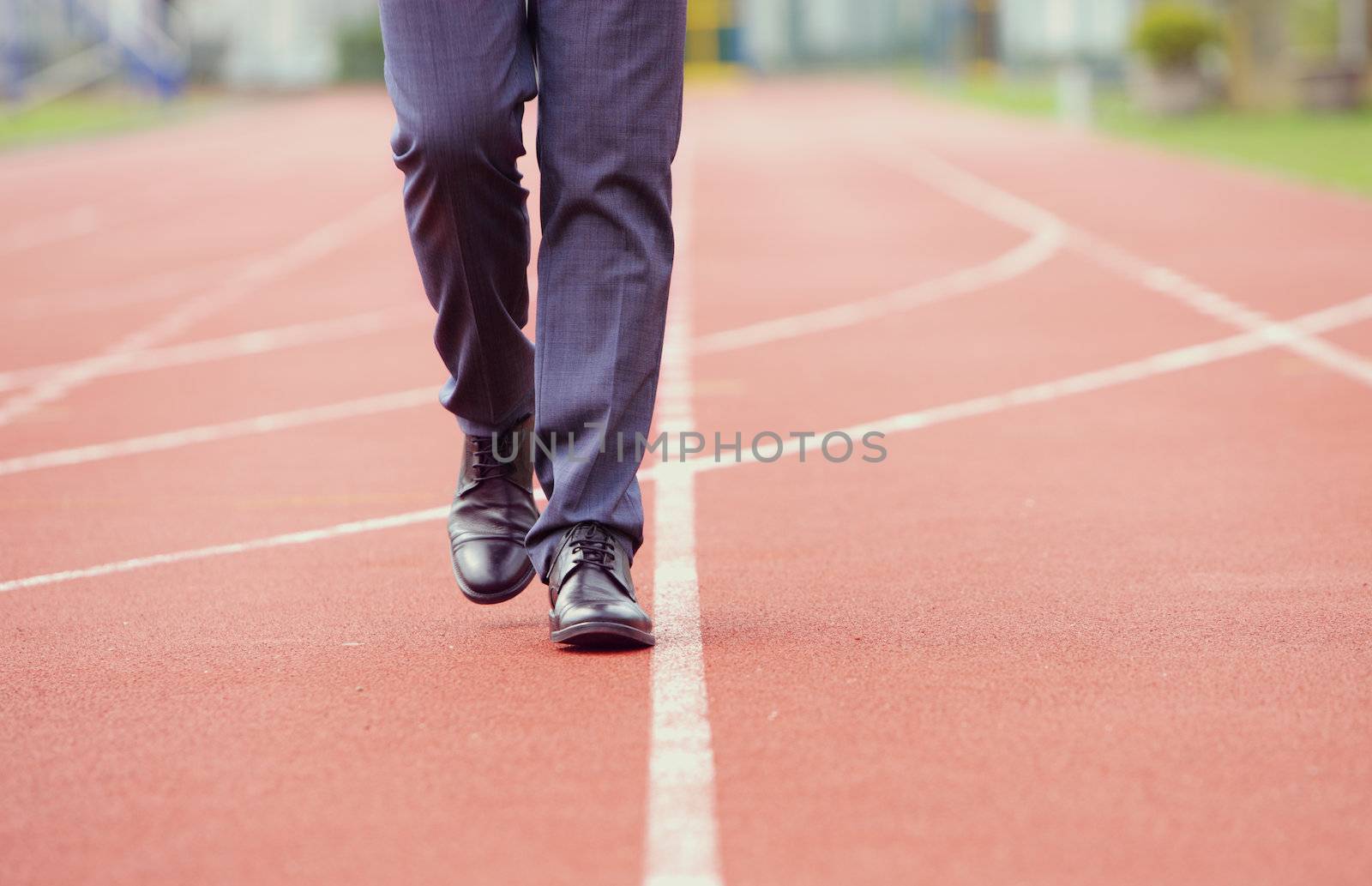 A business man is walking in the running track, close up
