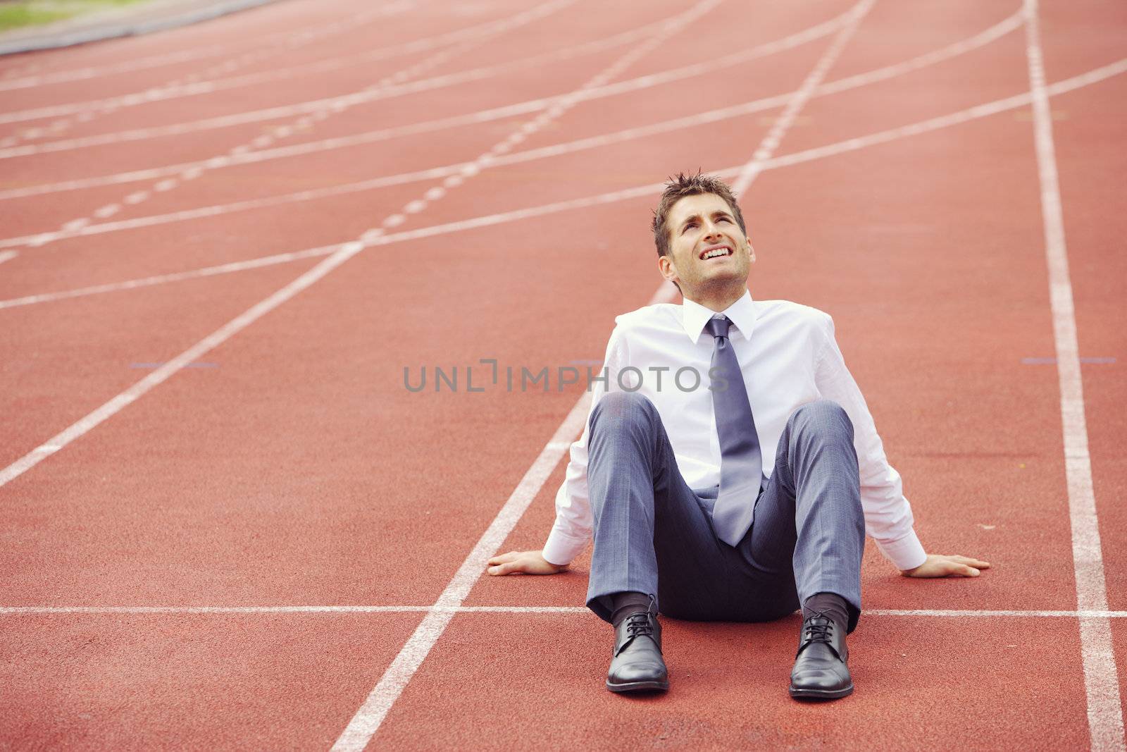 A businessman is sitting on the sports track, conceptual image