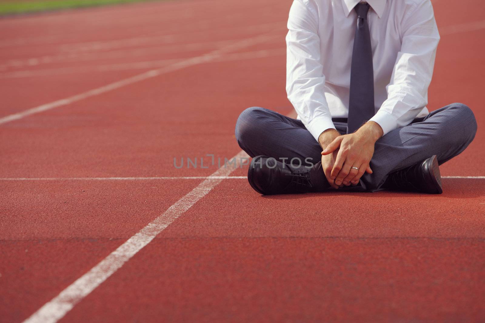 A businessman is sitting on the sports track, conceptual image