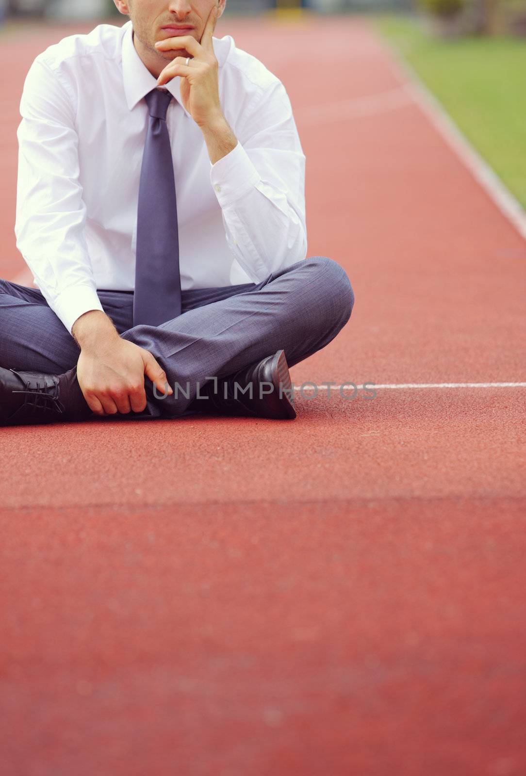 A businessman is sitting on the sports track, conceptual image