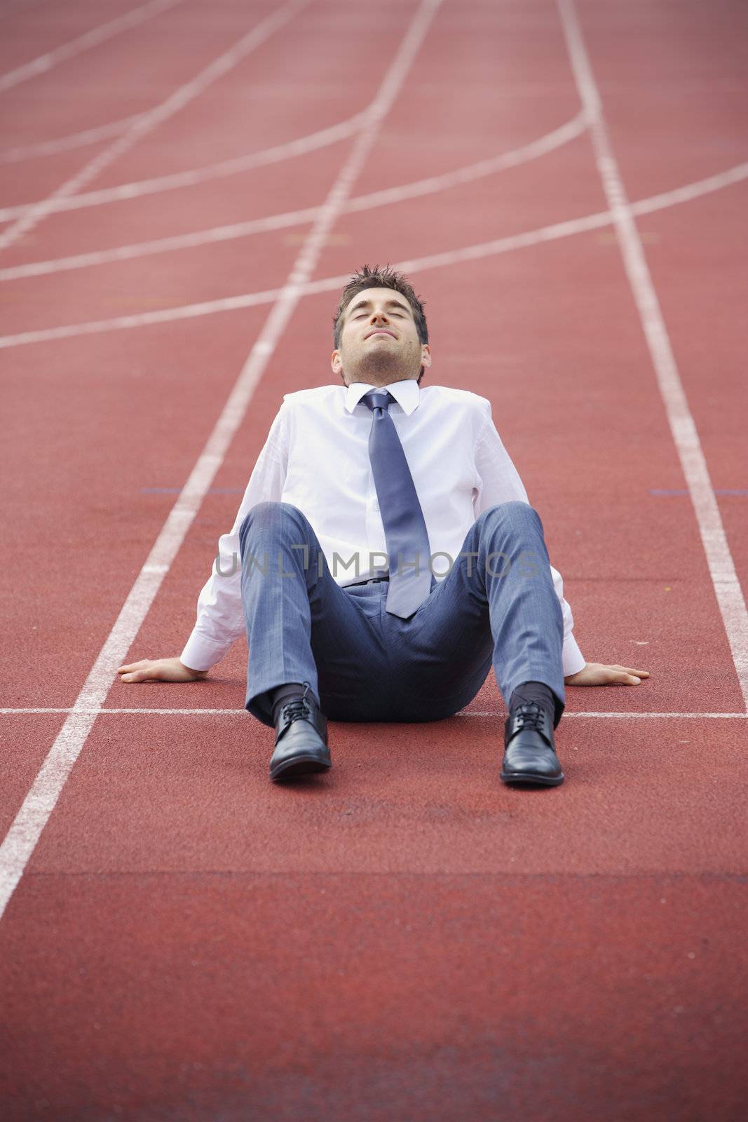 A businessman is sitting on the sports track, conceptual image